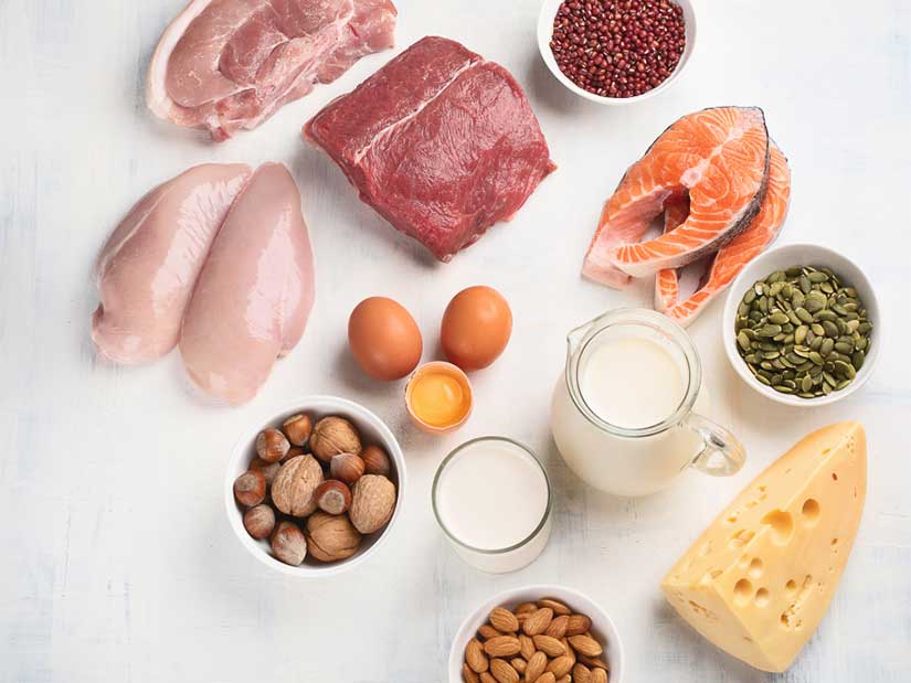 A selection of wholesome foods for a balanced diet, poultry, red meat, fish, eggs, milk, and nuts.